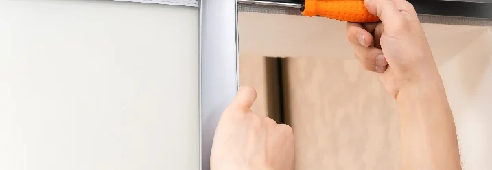 Person montiert Schiebetür mit Schraubendreher.